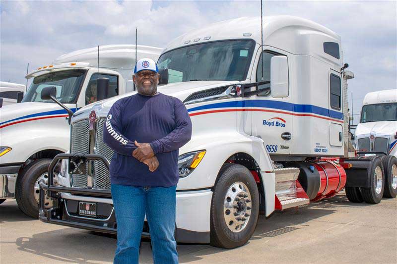 Boyd Bros. Transportation driver standing in front of power unit in truckyard